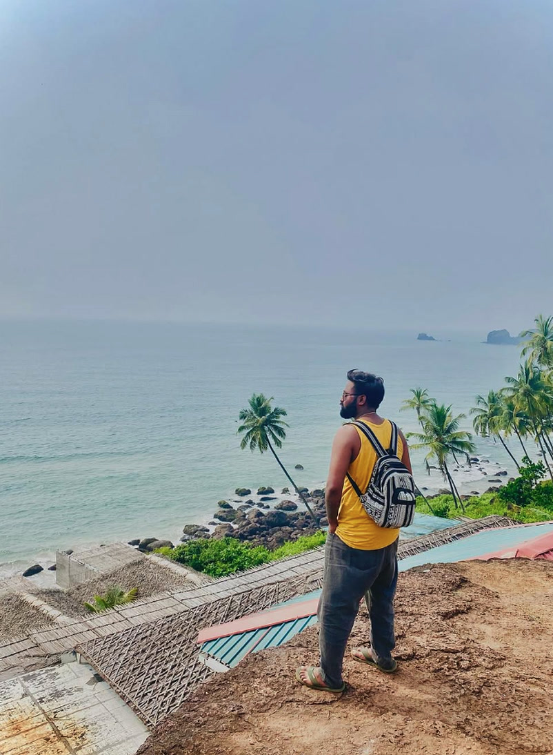 Devansh Singh standing on ocean cliff overlooking turquoise sea and palm groves for coastal destination weddings — Directed by Devansh Kushwah